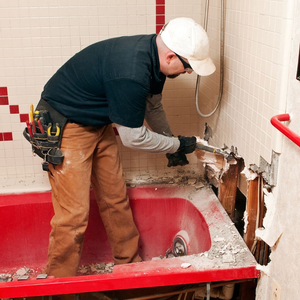 Tradesman removing an old bathtub during a bathroom strip-out