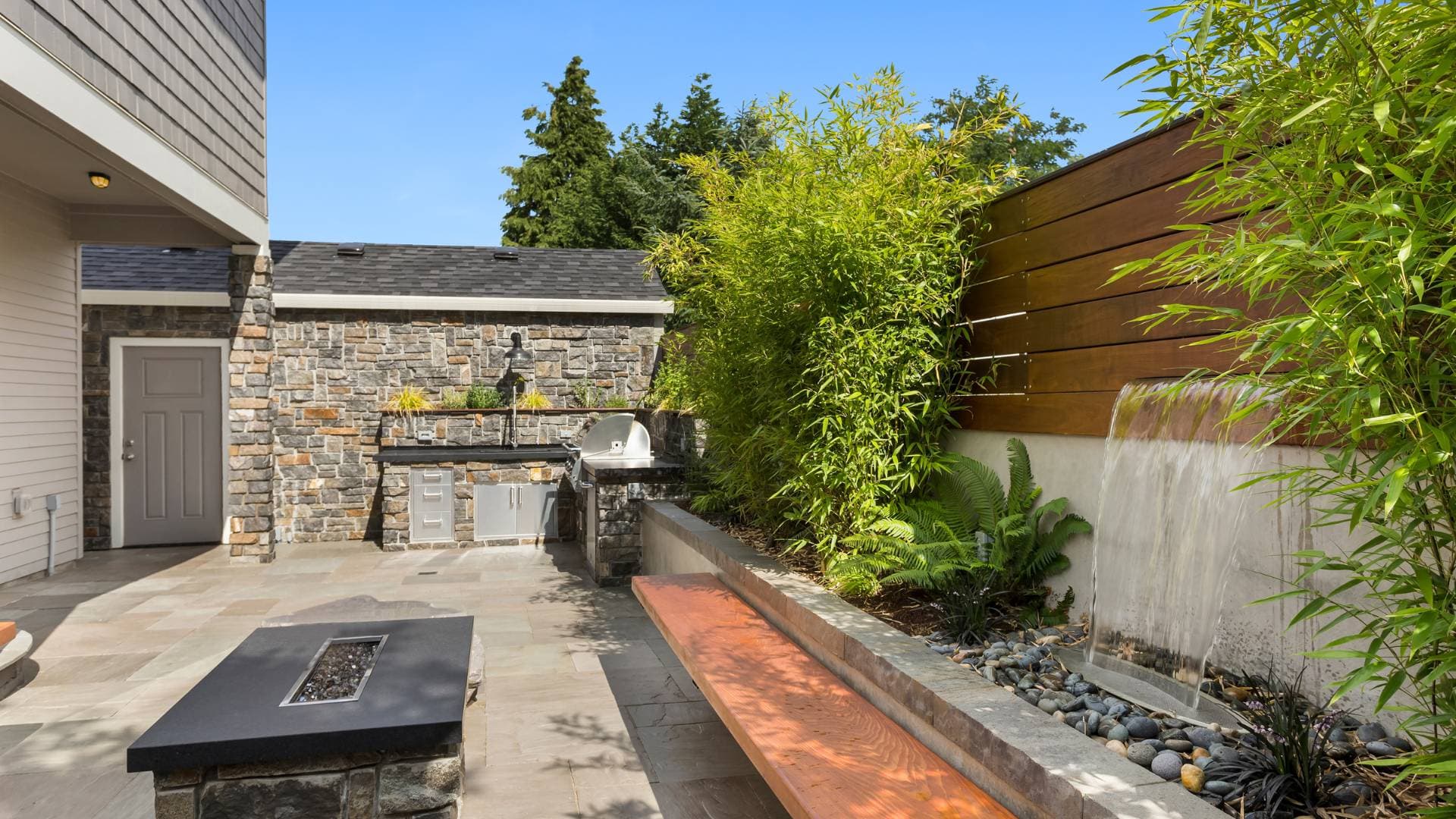 Stone-clad exterior with a fire feature and horizontal timber screen