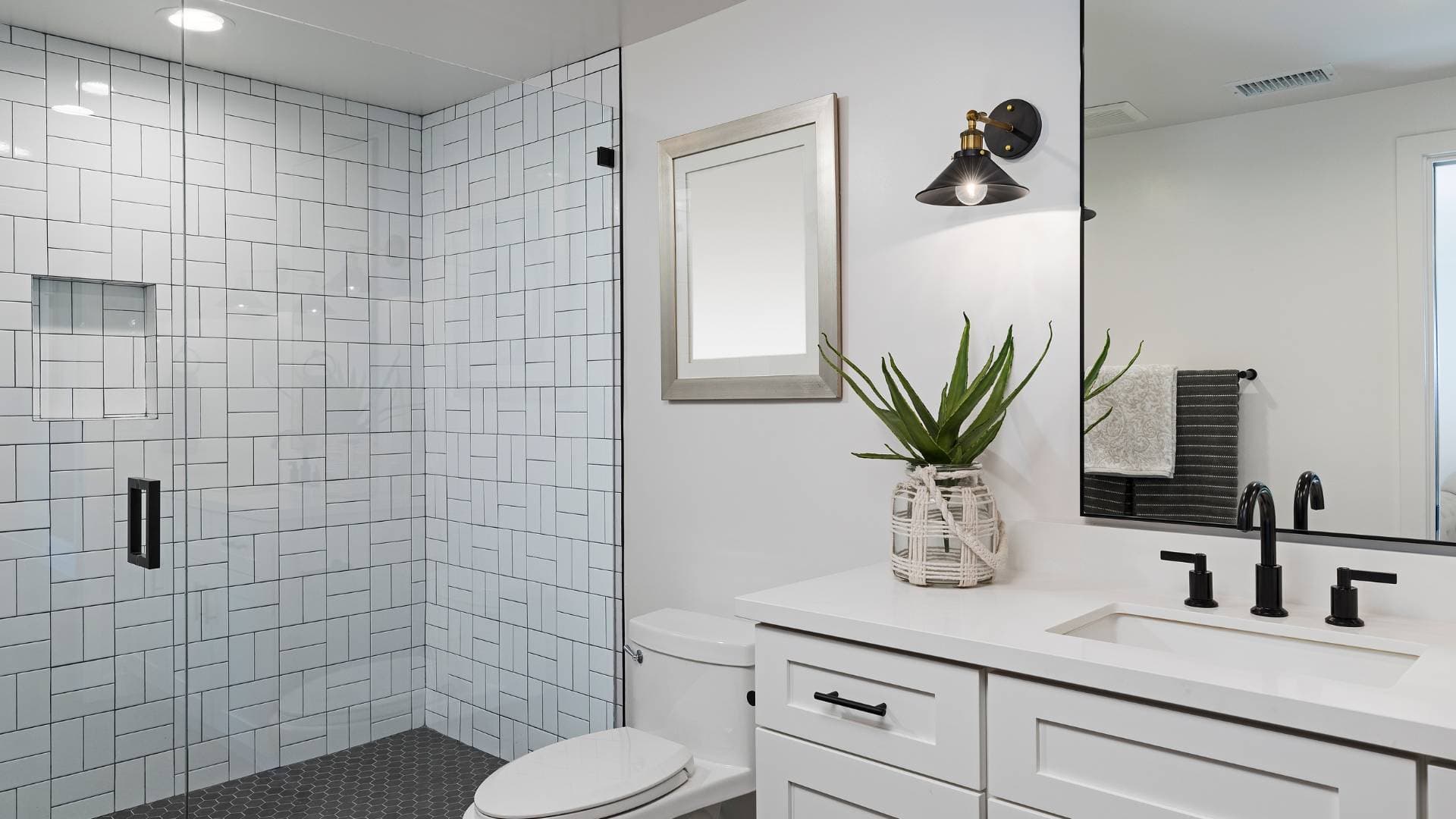 White metro-tiled bathroom with a black-framed shower screen