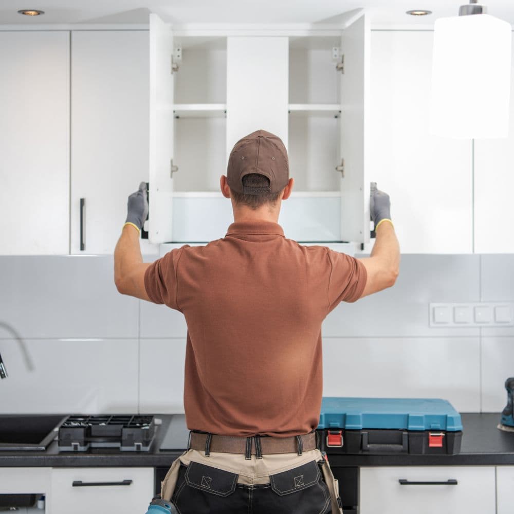 Carpenter fitting a wall cabinet during an interior fit-out
