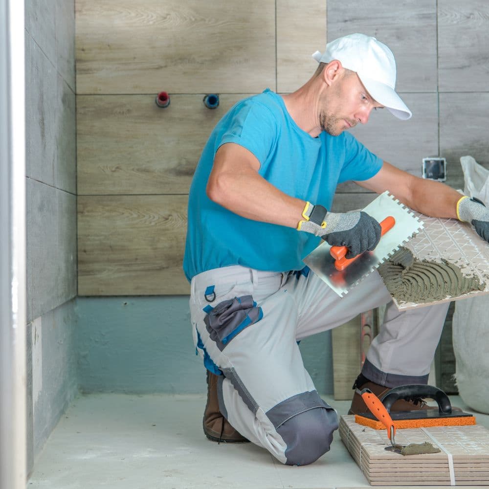 Installer setting wall tile in a shower under construction